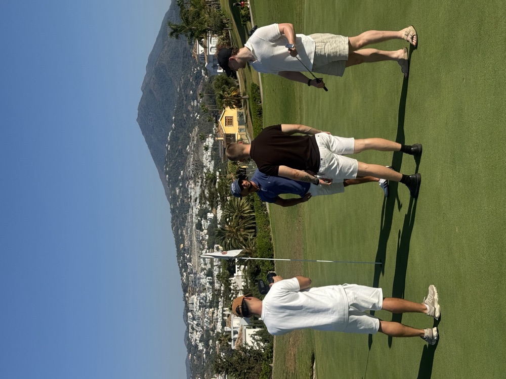 On the putting green with a mountain peak behind