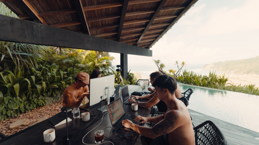 The crew building at laptops by the pool